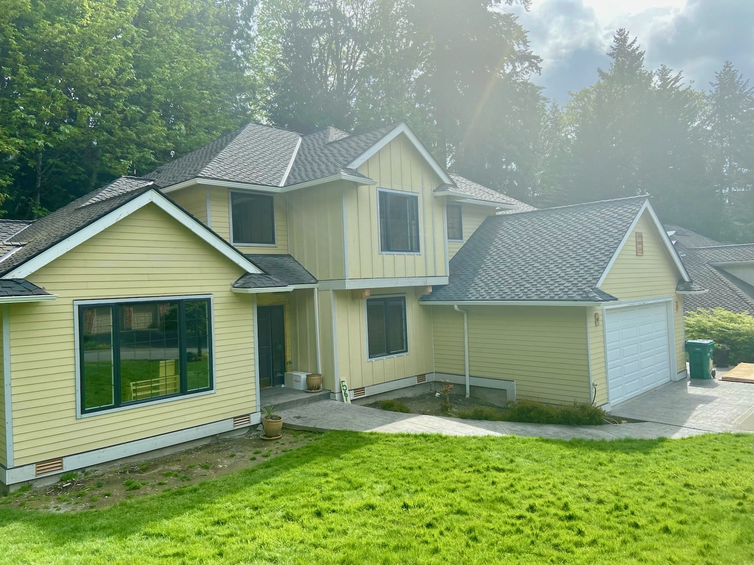 Finished pale yellow two-story Seattle home with new lap siding, board-and-batten gable and white trim around every window